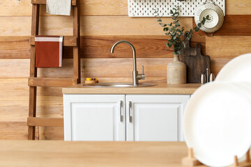 Plates on table and kitchen counter with sink near wooden wall