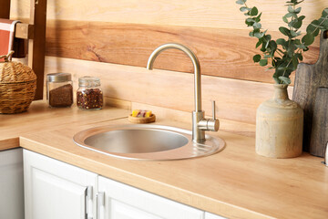 Wooden counter with sink and vase near wooden wall