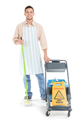 Young male worker of cleaning service with supplies in trolley on white background