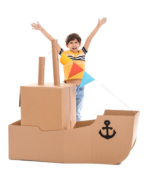 Cute little boy playing with cardboard ship on white background