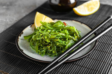 Plate with healthy seaweed salad on grey grunge background