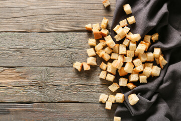 Many crunchy croutons on wooden table