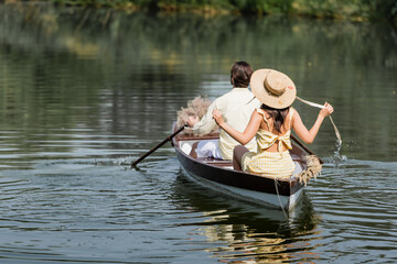 back view of woman in straw hat having boat ride with boyfriend.