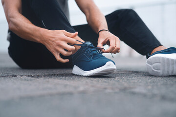 Tie them securely to avoid tripping. Closeup shot of an unrecognisable man tying his laces while...