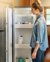 When hunger strikes.... Cropped shot of a young woman looking inside her fridge at home.