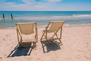 Two chairs on the beach near the sea.