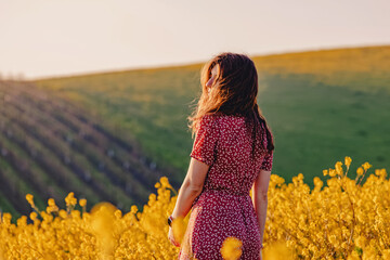 Portrait of young woman enjoying spring in a mustard field on sunny day
