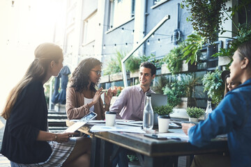 Productive meetings done over a cup of coffee. Shot of a group of designers having a meeting at a coffee shop.