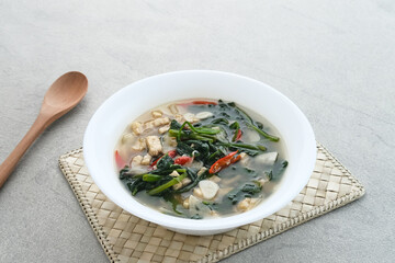 Tumis or Ca Kangkung Terasi with Tempeh, is one of Indonesian food. Served on white bowl on grey background. 
