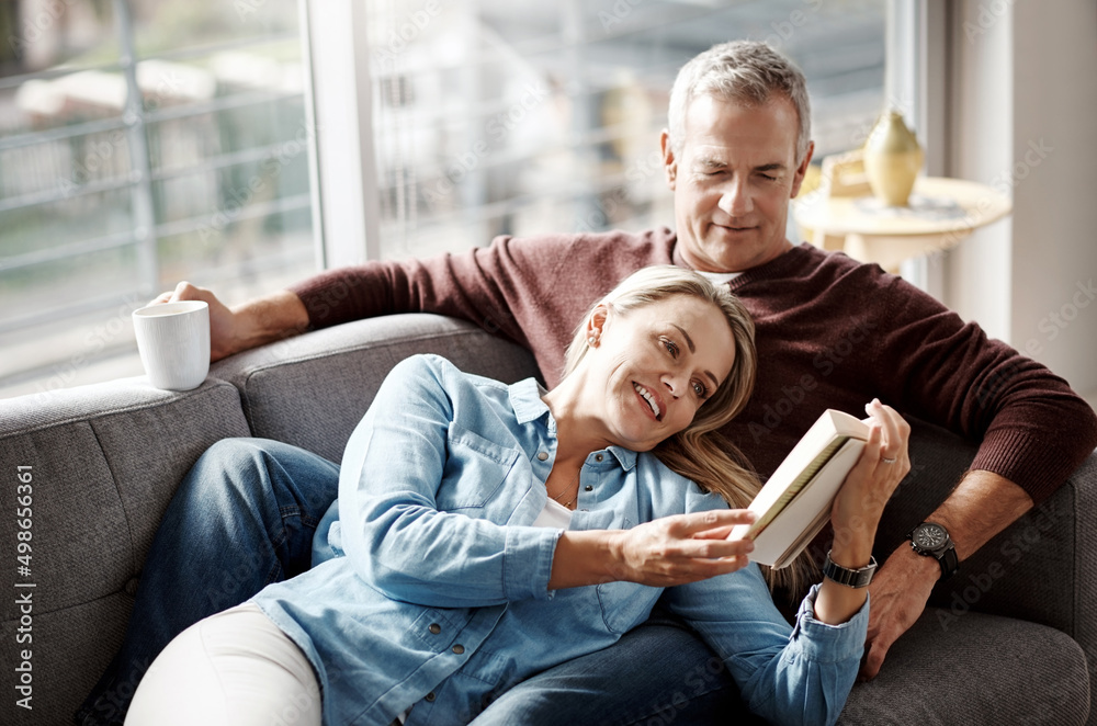 Poster weekends were made for winding down. shot of a mature couple reading a book together while relaxing 