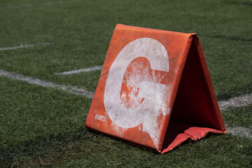 The letter G as it appears on a Football Grid goal ine or gridline representing a winning event or touchdown