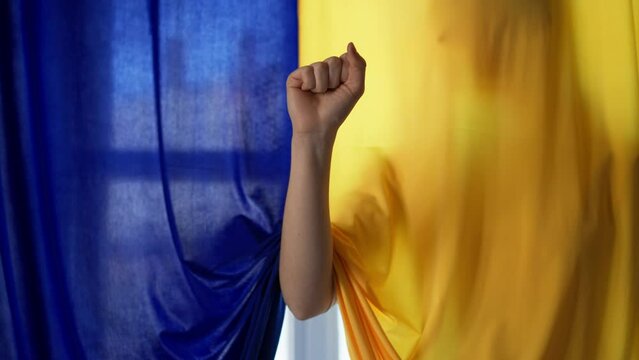 Silhouette of woman behind yellow and blue Ukrainian flag.