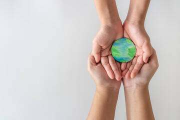 Adult and child hands holding the earth on hand.
