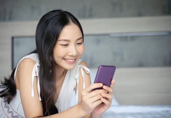 Obraz premium Young Asian woman using smart phone in bedroom happy and smile.