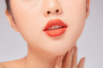 A close view of model showing lip posing with hand for cosmetic advertising