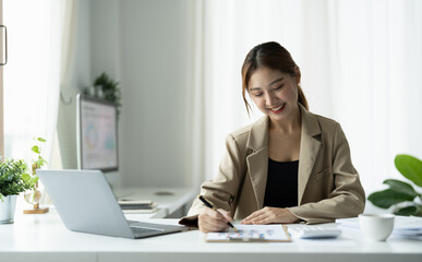 Business asian woman using laptop for do math finance on wooden desk in office, tax, accounting, financial concept