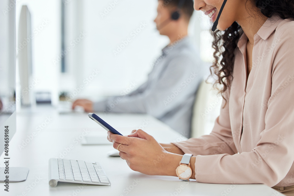 Aufkleber Logging inquiries through multiple digital portals. Closeup shot of a call centre agent using a cellphone while working in an office with her colleague in the background.