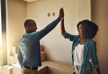 We got this babe. Shot of a cheerful young couple giving each other a high five inside at home...