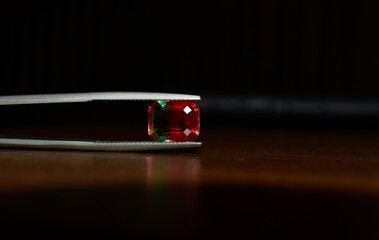 A beautiful red gem or ruby is placed on the ground.