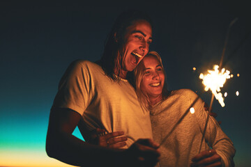 Their love shines brighter. Shot of a young couple playing with sparklers on the beach at night.