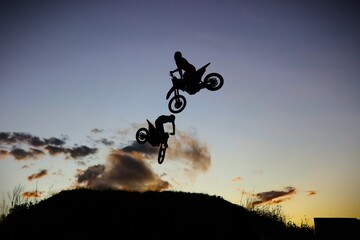 Silhouette of motocross riders jumping