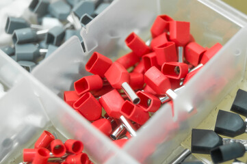 A set of red crimp terminals for electrical wires. Crimping sleeves of different sizes. Plastic spare parts box for electrician. Toolbox. Selective focus