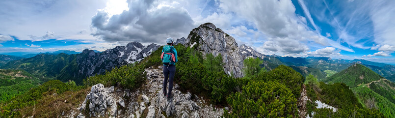 Fototapeta na wymiar Woman with backpack and helmet hiking on path with scenic view on mountains Kamnik Savinja Alps in Carinthia, border Slovenia Austria. Velika Baba, Vellacher Kotschna. Mountaineering. Freedom concept