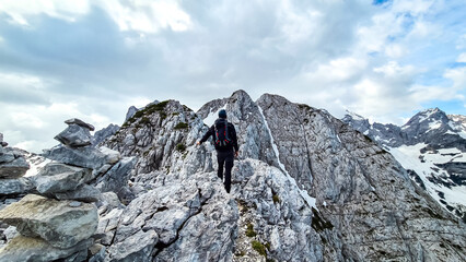 Fototapeta na wymiar Man with backpack and helmet hiking on path with scenic view on mountains Kamnik Savinja Alps in Carinthia, border Slovenia Austria. Velika Baba, Vellacher Kotschna. Mountaineering. Freedom concept