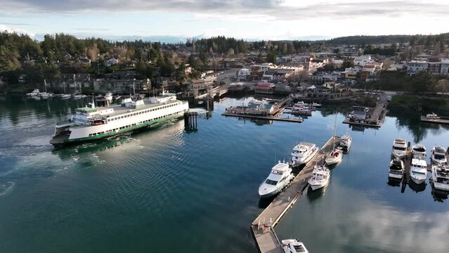 Cinematic 4K aerial drone footage of the Washington State Ferry arriving in Port and town of Friday Harbor with the ferry terminal, commercial zone, downriggers in the San Juan Islands