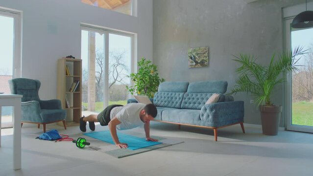 Adult young man is exercising at home doing push up exercise. The athlete doing push up exercise stimulating the work of all muscles of the body