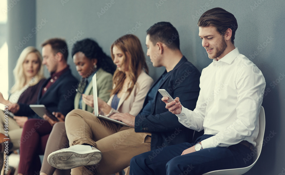 Poster The queue to success. Shot of a group of businesspeople using different wireless devices while waiting in line for an interview.