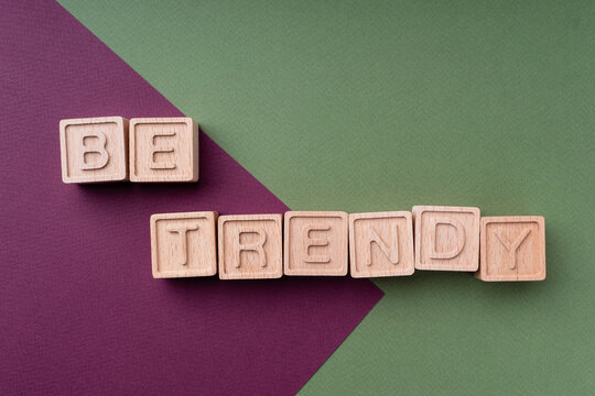 Be trendy. Inscription on a bright background of burgundy and green. Color trends 2022. The text is made up of wooden ecological cubes on a paper background. Fashion and design concept