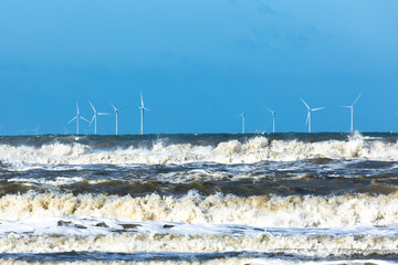 Offshore windmill park in a stormy north sea with spindrift waves