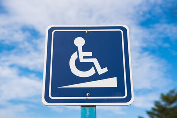 Blue handicapped wheelchair sign car park in outdoors with cloudy blue sky background.