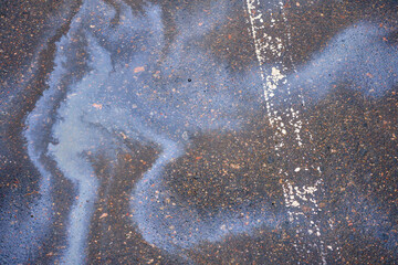 Gasoline spill on asphalt in a car park as a texture or background.
