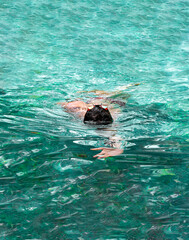 Man swimming on its back in the pool. Triathlon fitness athlete swimming training. Swimmer person floating in turquoise water, vertical. Sports and fitness cardio exercises.