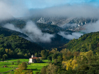 church landscape in the valley with mountain background with banks of fog