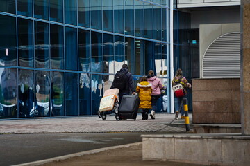 Almaty, Kazakhstan - 03.16.2022 : Passengers with luggage walk past the glass windows of the airport building