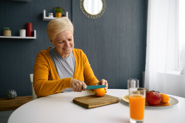 Elderly woman chopping fruits for fresh juice