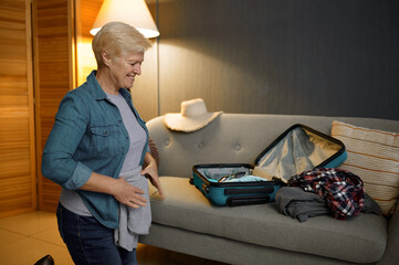 Senior woman packing luggage for new journey