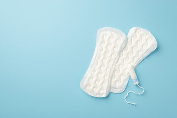Top view photo of two panty liners and tampon on isolated pastel blue background with copyspace