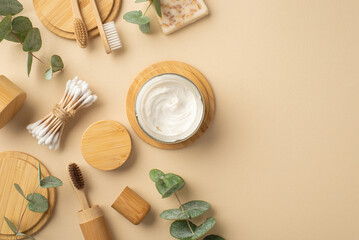 Naklejka na ściany i meble Natural cosmetics concept. Top view photo of jar with toothpaste soap toothbrushes cotton buds eucalyptus and wooden stands on isolated beige background with copyspace