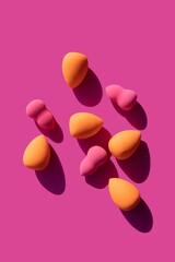 makeup sponges on a pink background with hard shadows from the sun. High quality photo