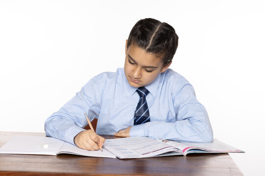 young girl of primary school sitting in classroom writing isolated on white background