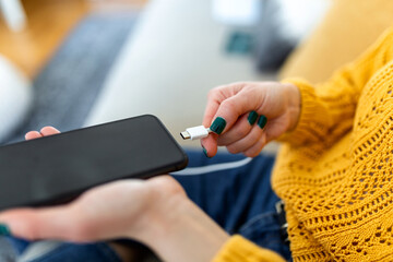 Woman hands plugging a charger in a smart phone. Woman using smartphone with powerbank, charging...