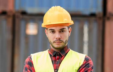 Portrait young Caucasian male engineer in transport industry wearing helmet, safety waistcoat, arm crossed, looking at camera. Smart manager or executive have confidence, leadership work in logistics.
