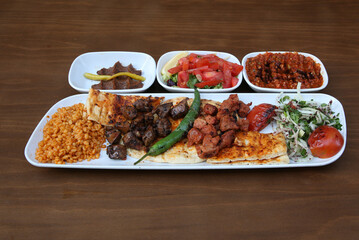 Liver kebab and lamb shish kebab are on the plate, accompanied by salad, spicy paste and raw meatballs