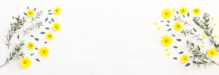 Top view image of yellow chrysanthemum field flowers composition over wooden white background. Flat lay