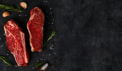 Raw fresh meat striploin beef steak on dark background with copy space
