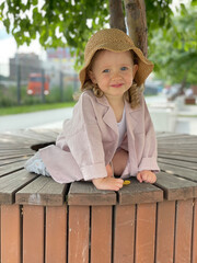 Baby girl in pin clothes and a straw hat
